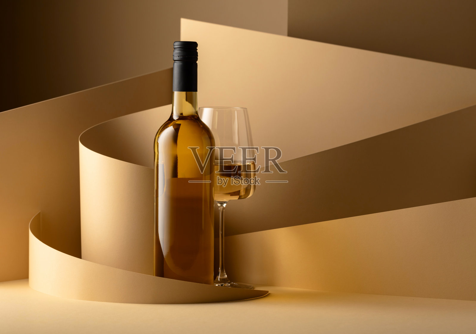 米色背景上的一瓶和一杯白葡萄酒。照片摄影图片