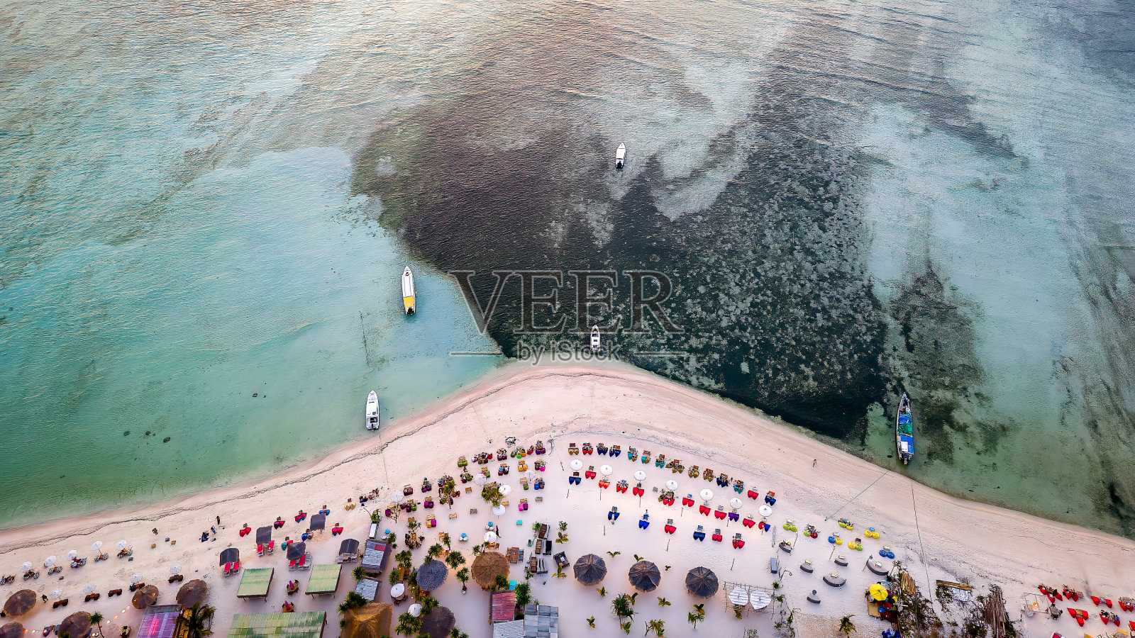 日落时分,一个小岛上的热带沙滩上的桌子和座位的鸟瞰图照片摄影图片