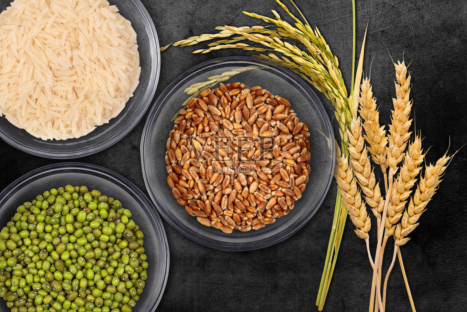 绿豆,白米和棕色小麦种子在一个黑暗的抽象背景透明玻璃罐俯视图。照片摄影图片