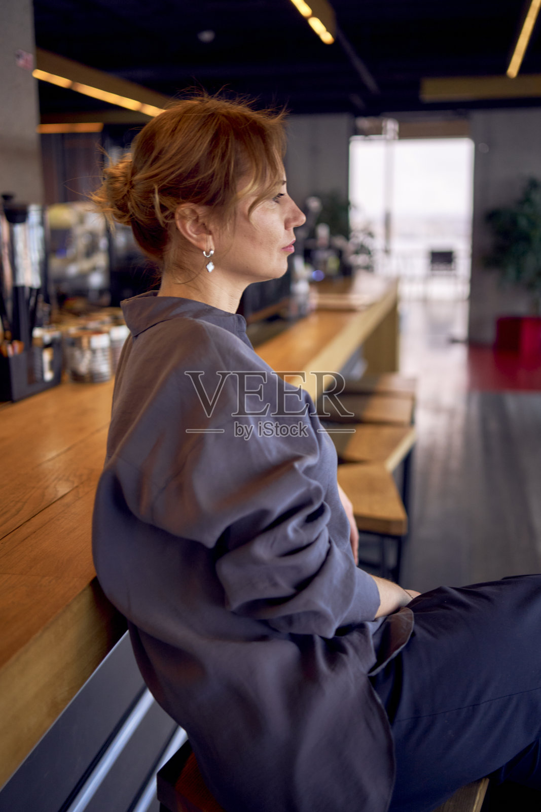 疲惫的中年妇女在酒吧里,穿着中性的设计,宽腿裤和丝绸衬衫照片摄影图片