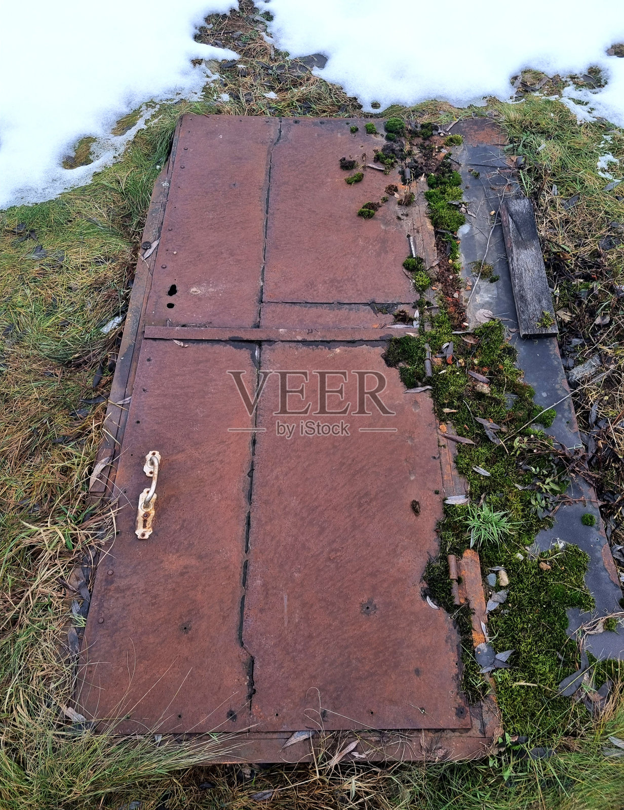 出奇地。冬天。冬天地上的雪里,生锈的老铁门。避难所入口照片摄影图片