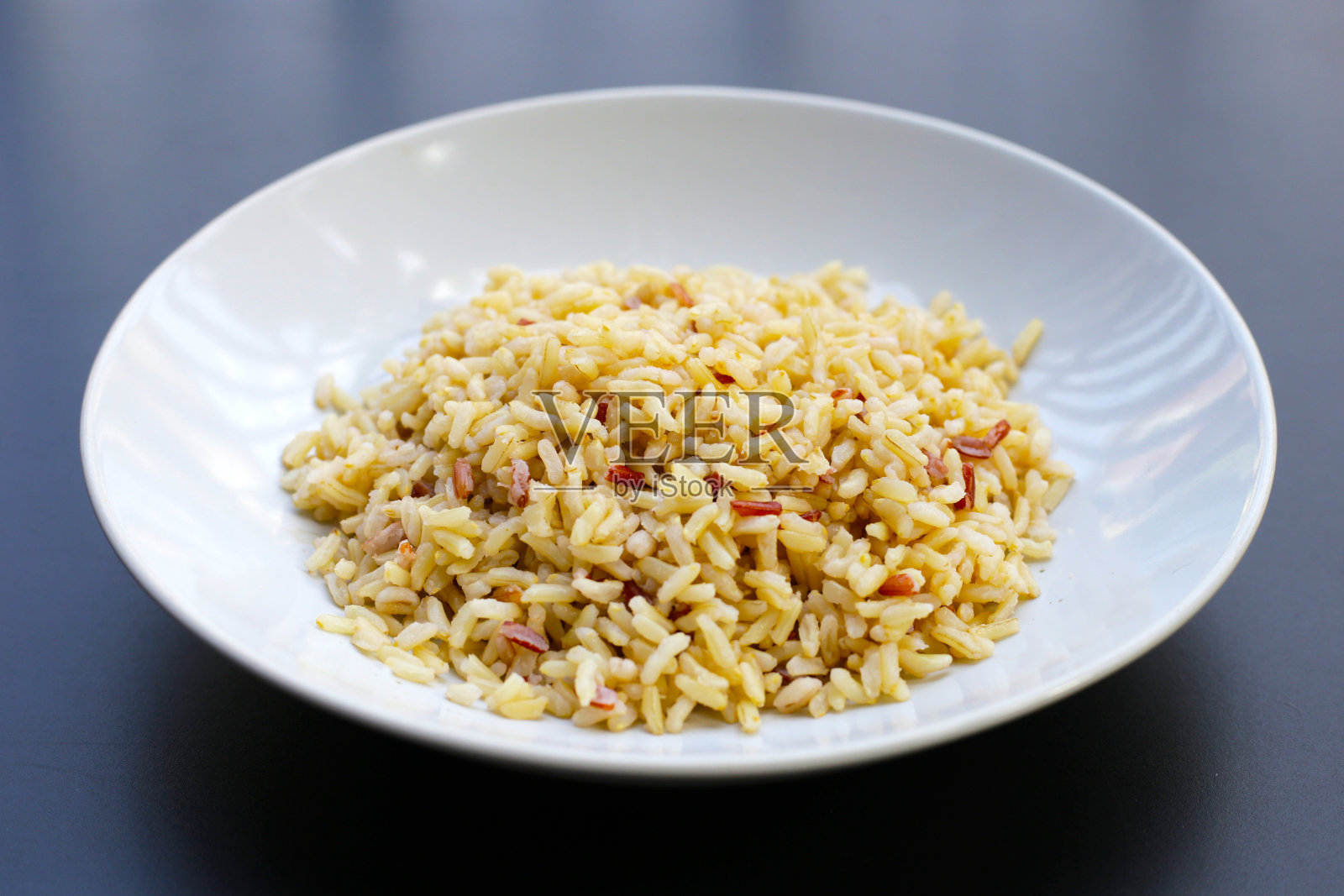 黑底白盘煮熟的糙米。照片摄影图片