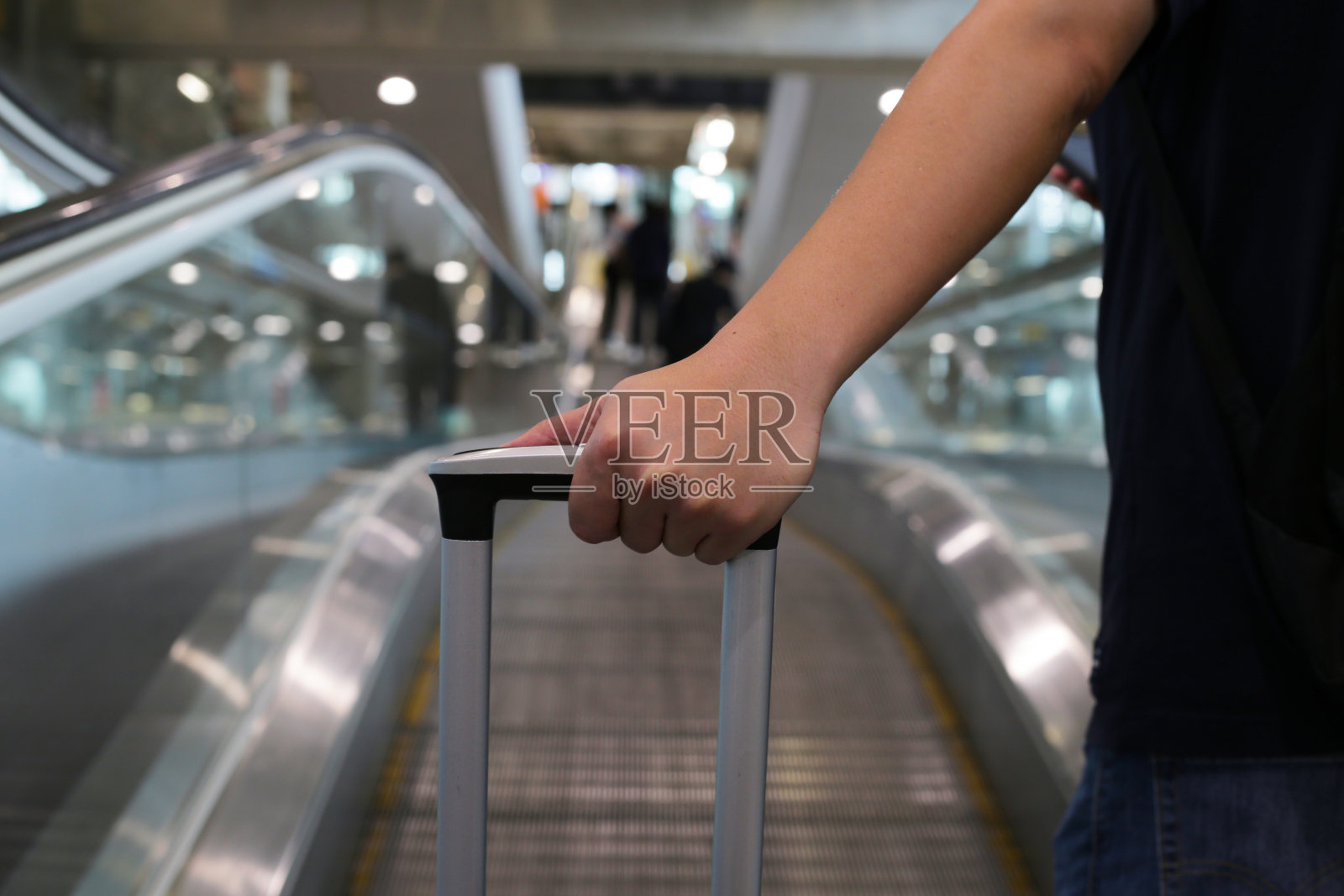 男子在自动扶梯上用手触摸行李照片摄影图片