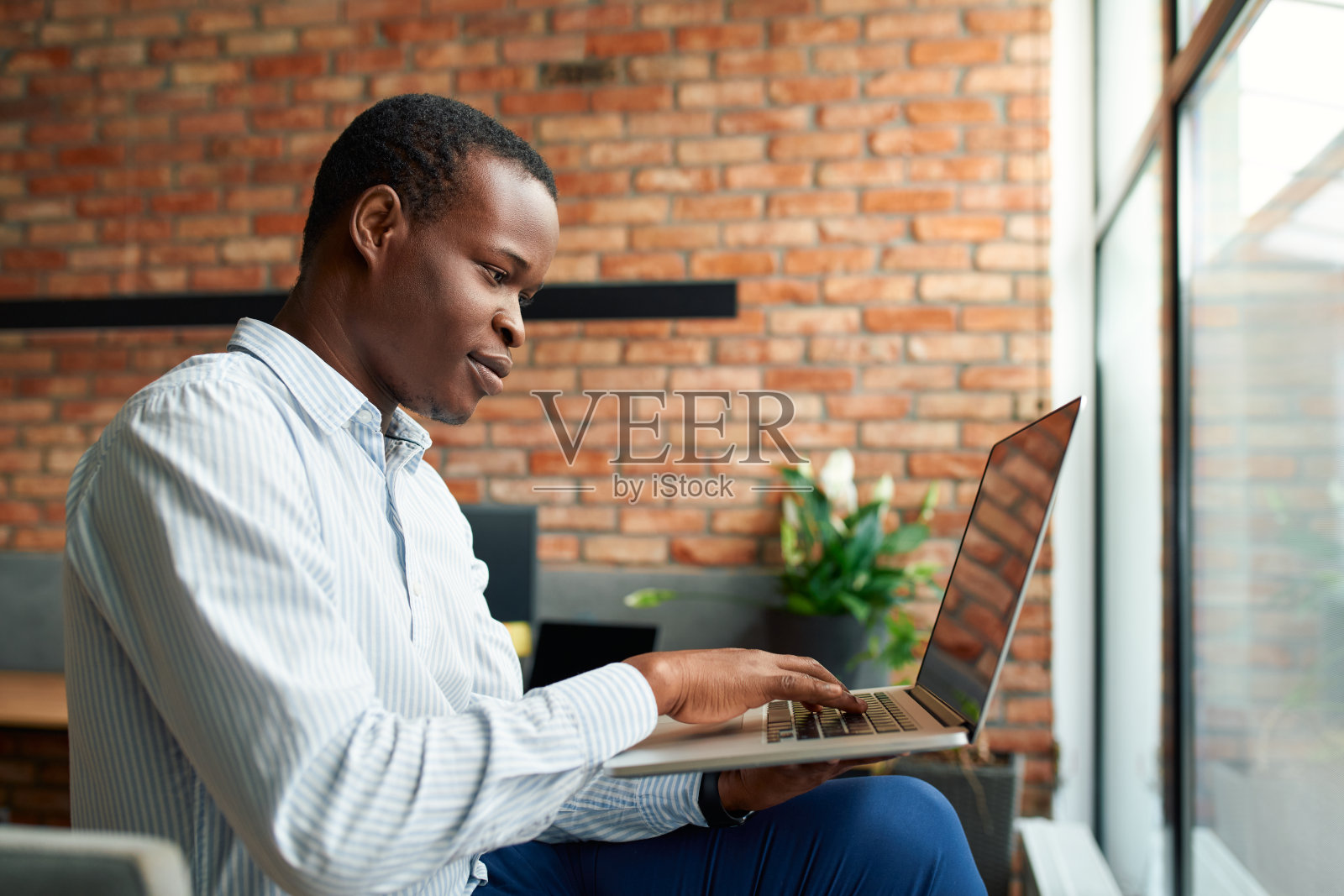 年轻的商人放松地坐在办公室里使用笔记本电脑照片摄影图片