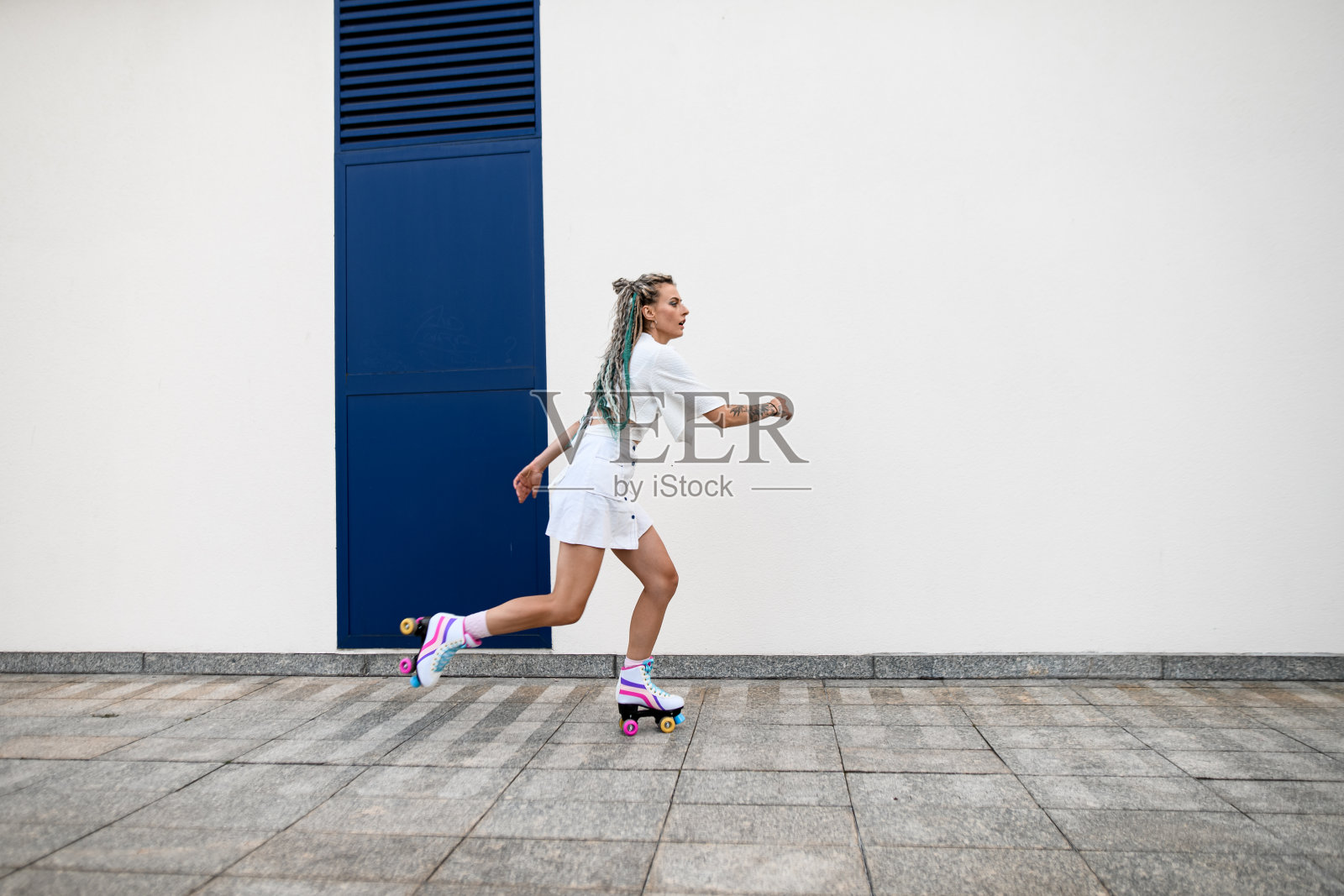 年轻女子穿着复古的轮滑鞋,在白色的墙壁背景下照片摄影图片