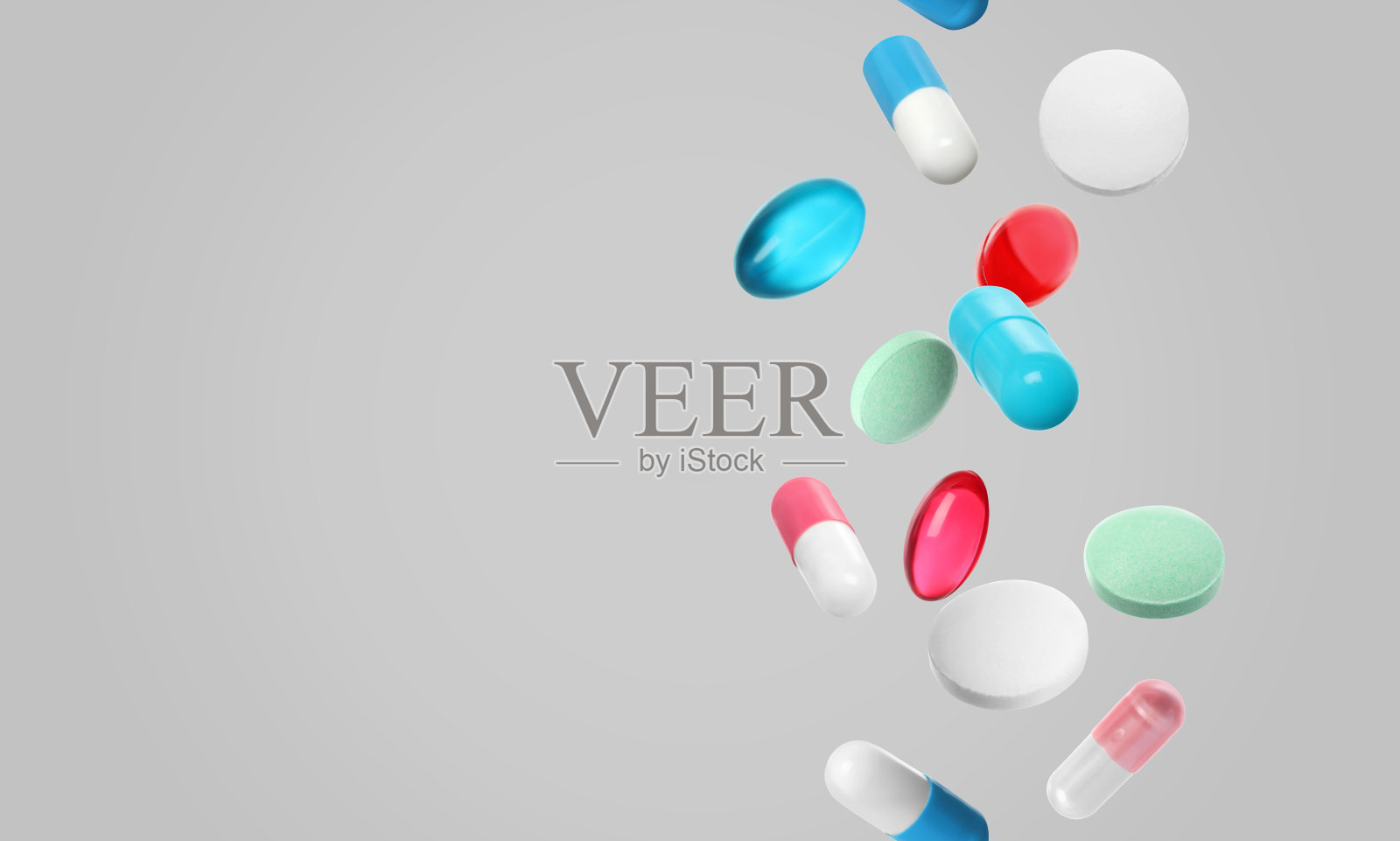 许多不同颜色的药丸落在浅灰色的背景上,为文字留出空间照片摄影图片