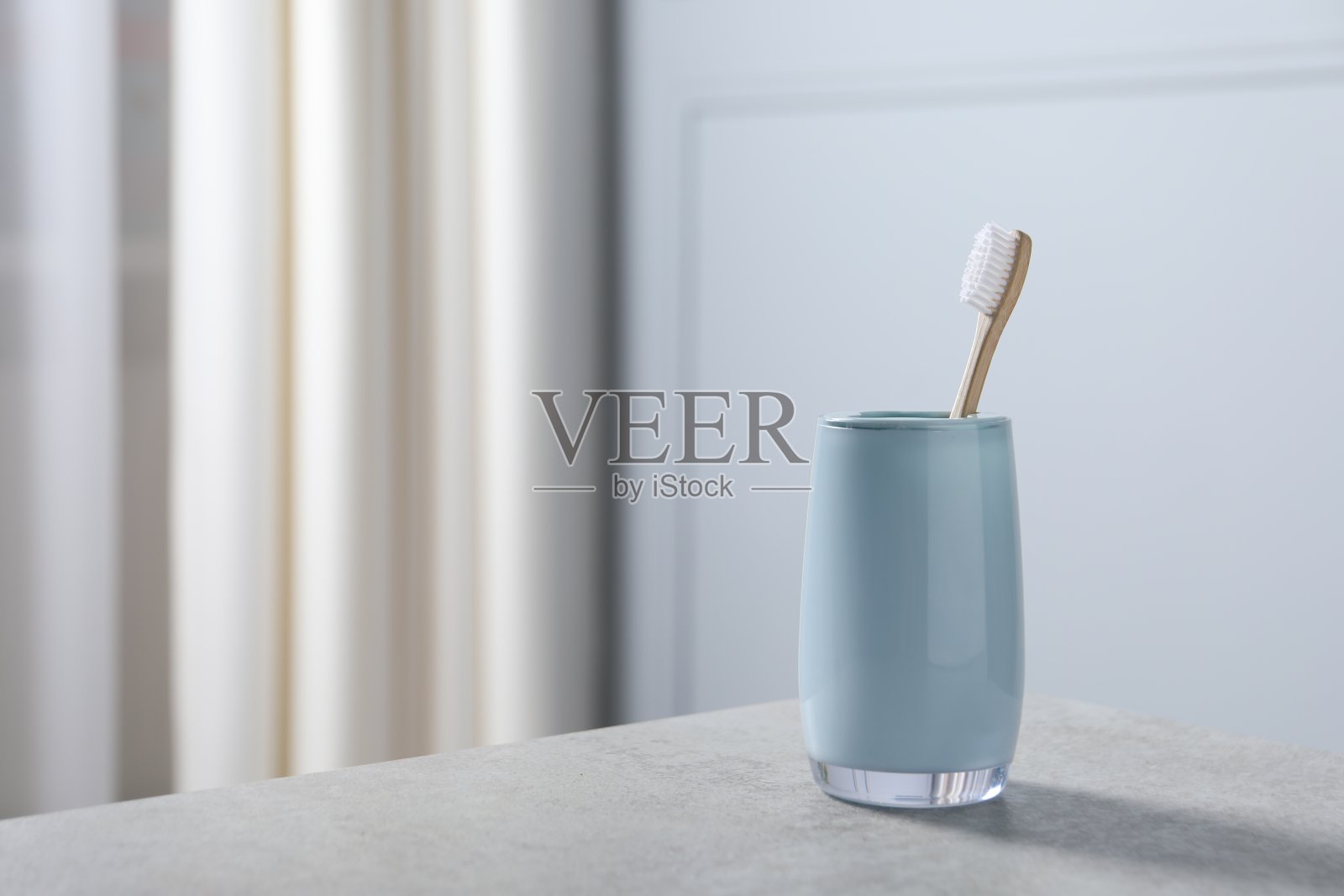 室内浅灰色桌子上的竹制牙刷架。文本空间照片摄影图片