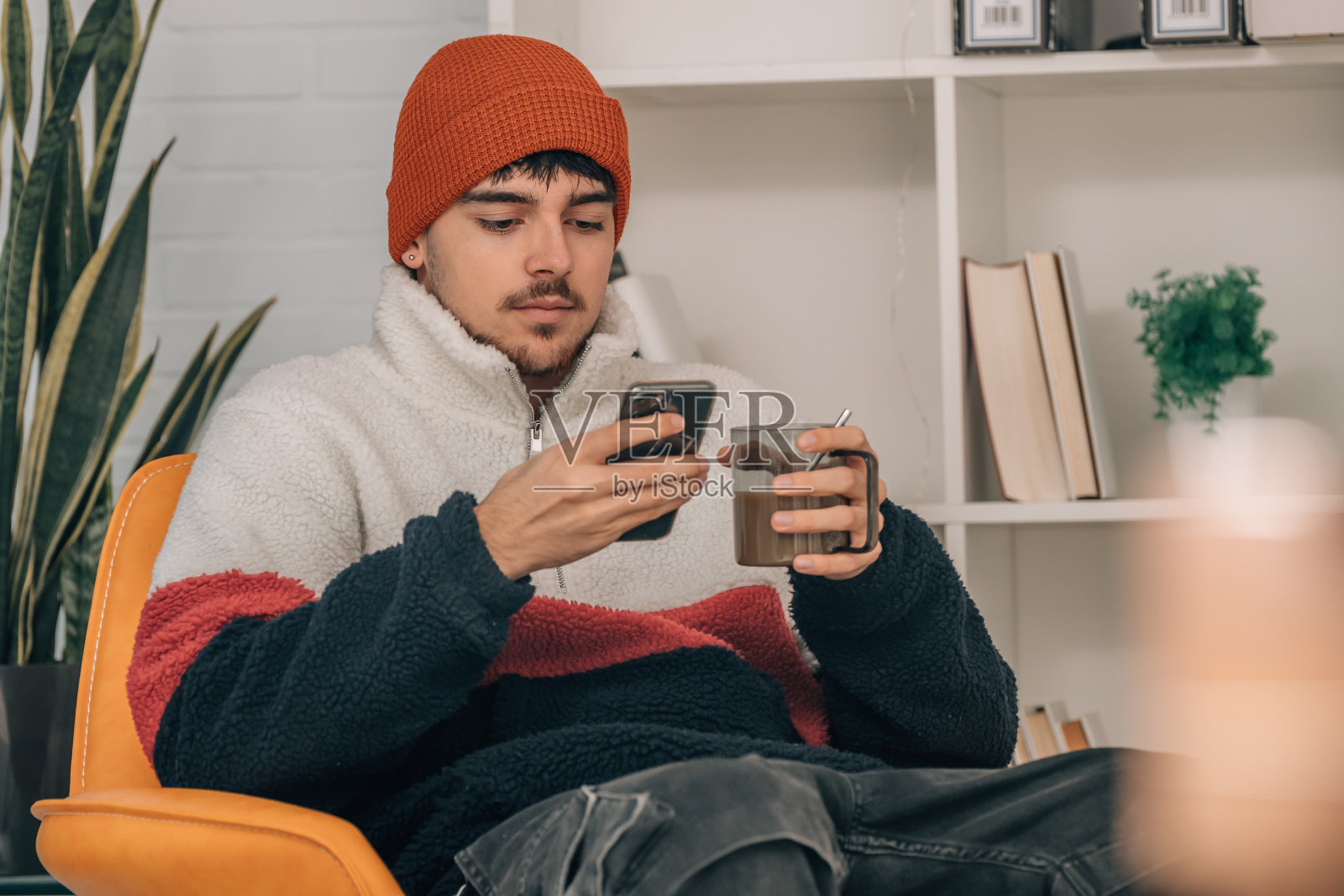 年轻人在家里用一杯温暖的咖啡和手机照片摄影图片
