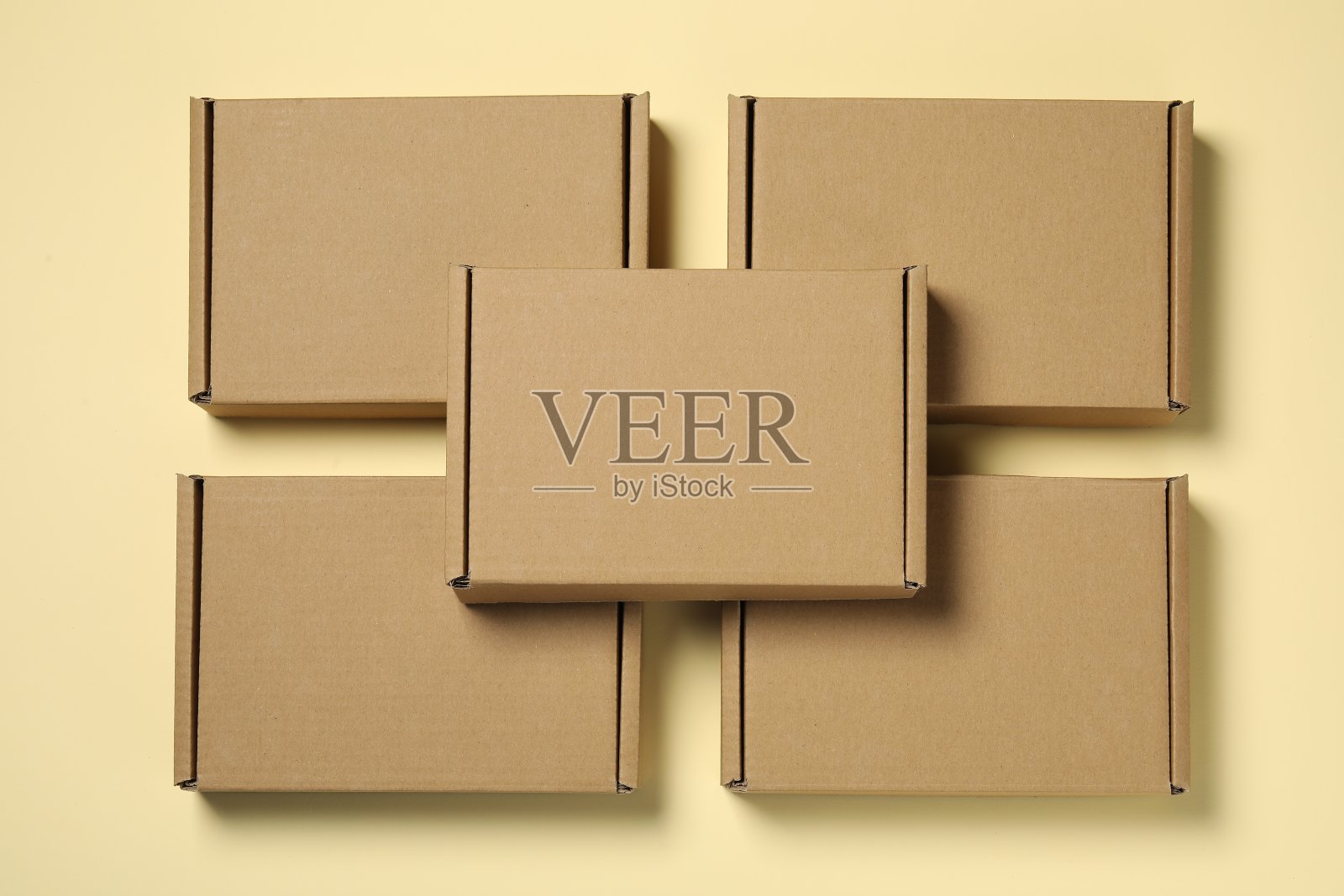 许多封闭的纸板箱在淡黄色的背景上,平躺着照片摄影图片