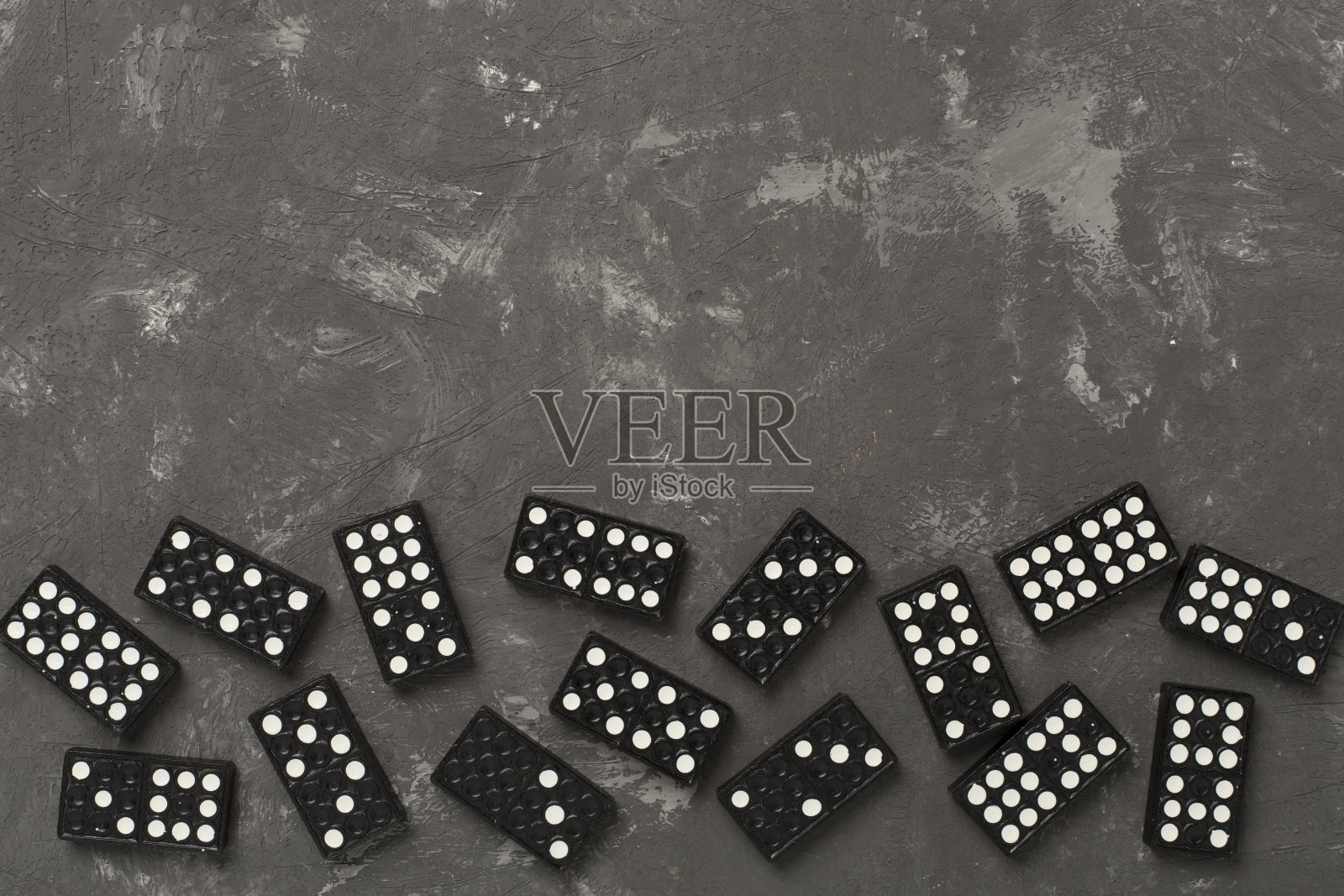 混凝土背景上的黑色多米诺骨牌,俯视图照片摄影图片