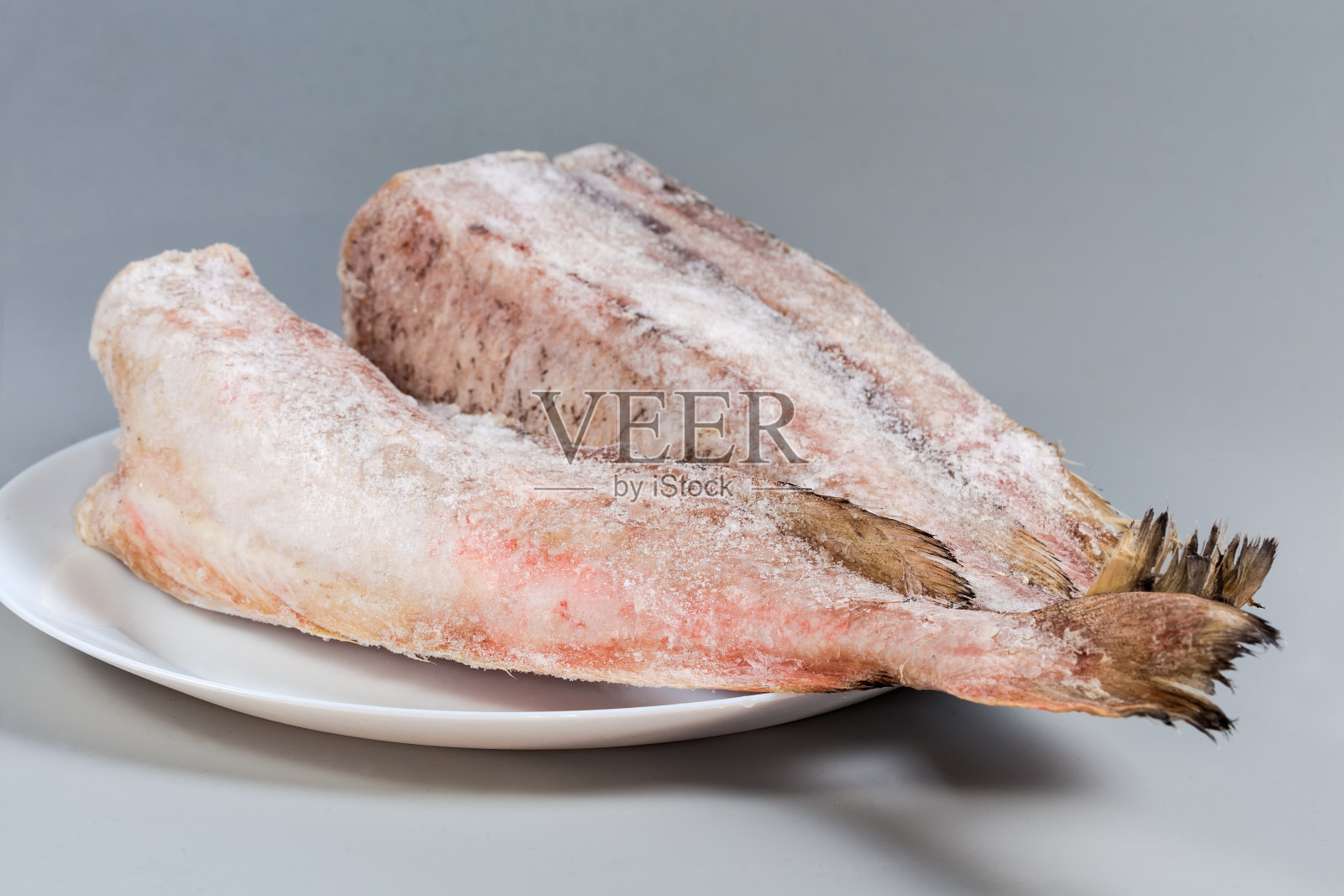 灰色背景盘上的冷冻红鳕鱼尸体照片摄影图片