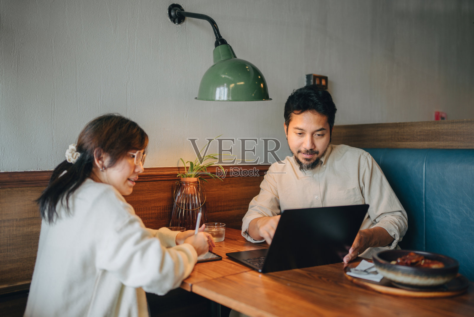 一群穿着便服的亚洲企业家在餐厅用电脑聊天。照片摄影图片