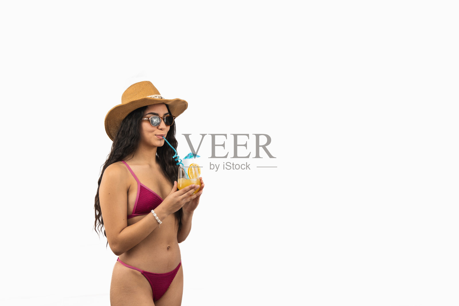 身穿比基尼的拉丁女子在白色背景上享受着热带鸡尾酒和太阳帽的海滩时光照片摄影图片