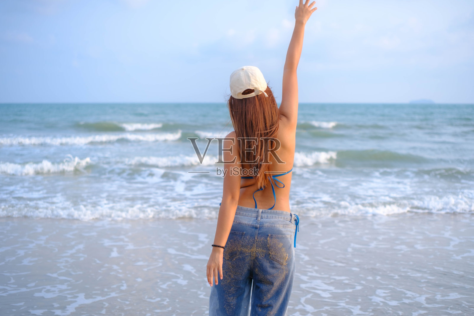 美丽的亚洲模特戴着帽子,穿着泳衣,在海滩上摆姿势。照片摄影图片