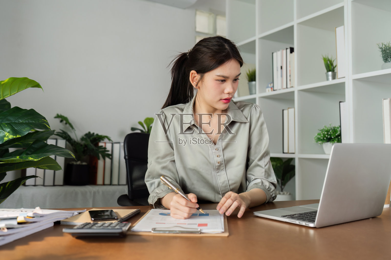 商业财务女性坐在办公桌前,有笔记本电脑和文件财务剪贴板照片摄影图片