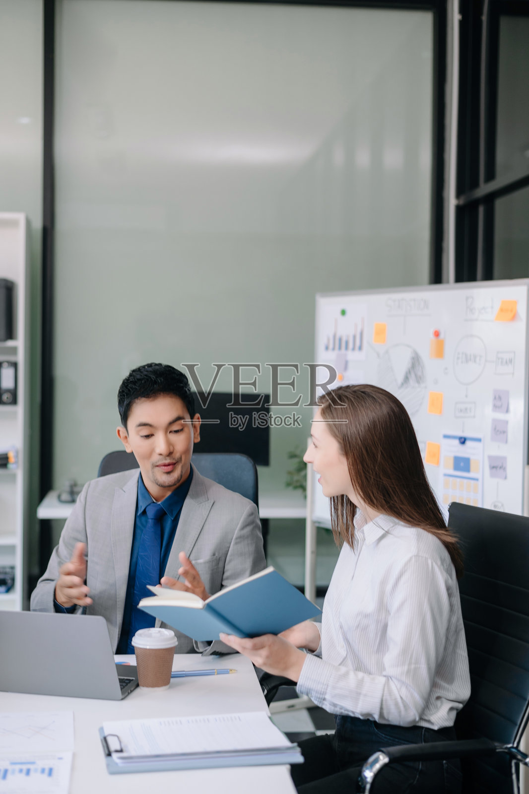 在办公室里合作一个新项目时快乐的商人。一群使用笔记本电脑和平板电脑的不同商人照片摄影图片