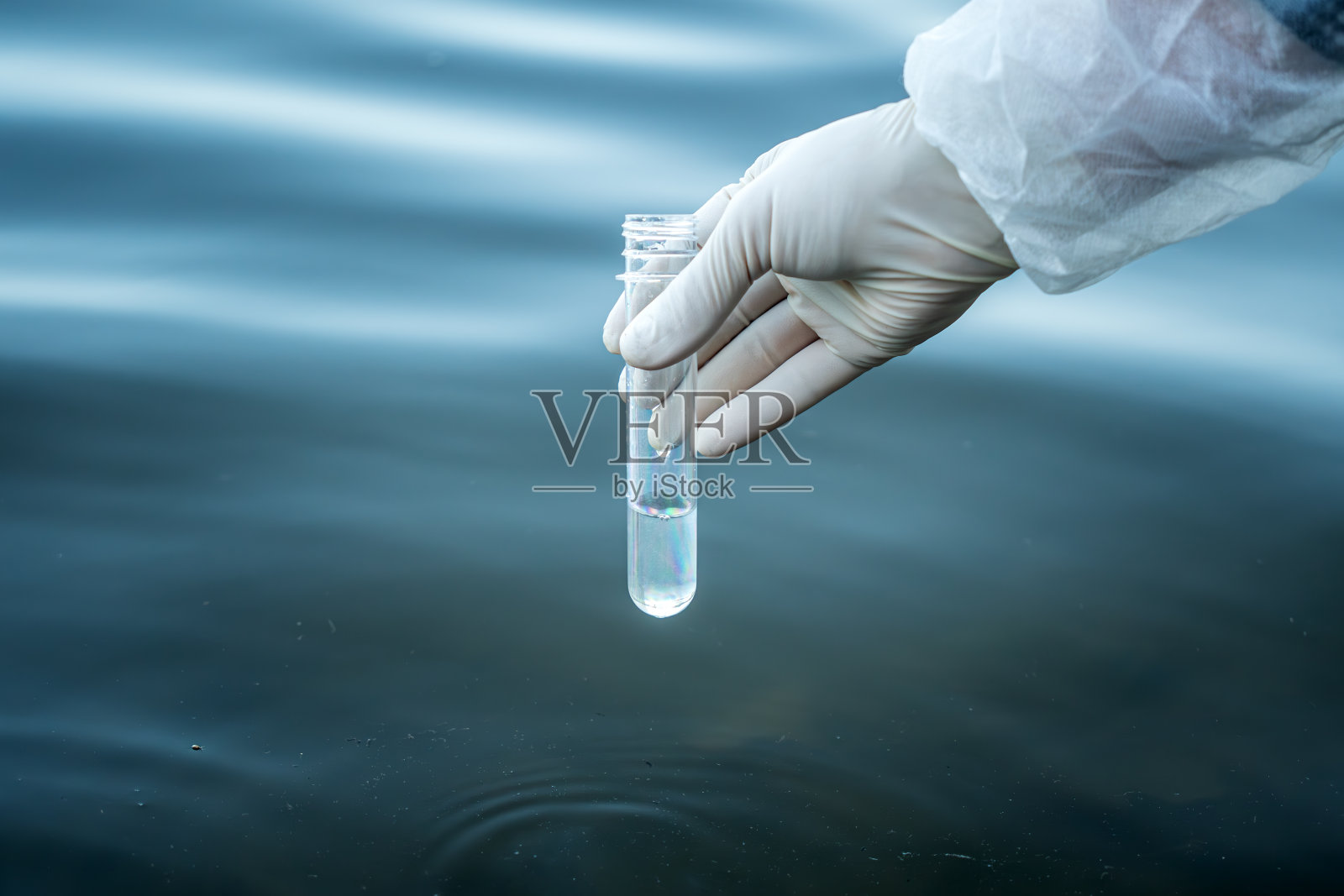 天然水库水质检测。一个人拿着试管和水检查它的纯度。照片摄影图片