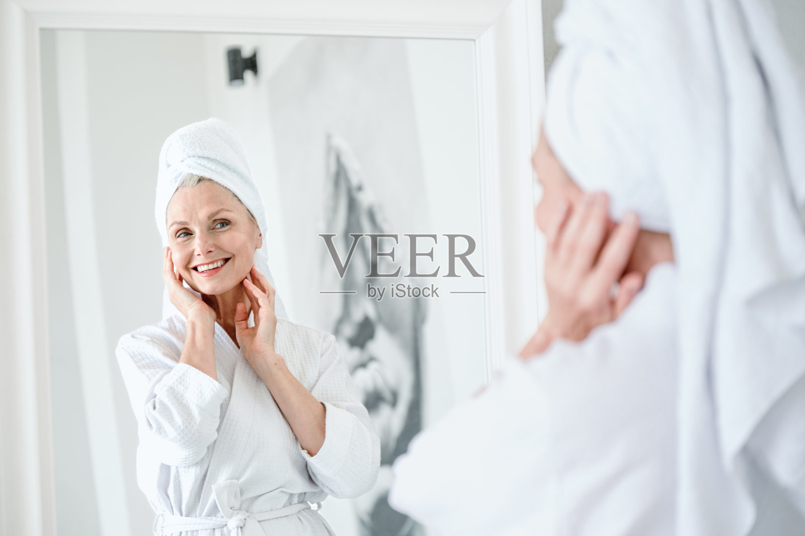 40多岁的老妇人在抗衰老治疗后用毛巾敷头,脸上露出快乐的笑容照片摄影图片