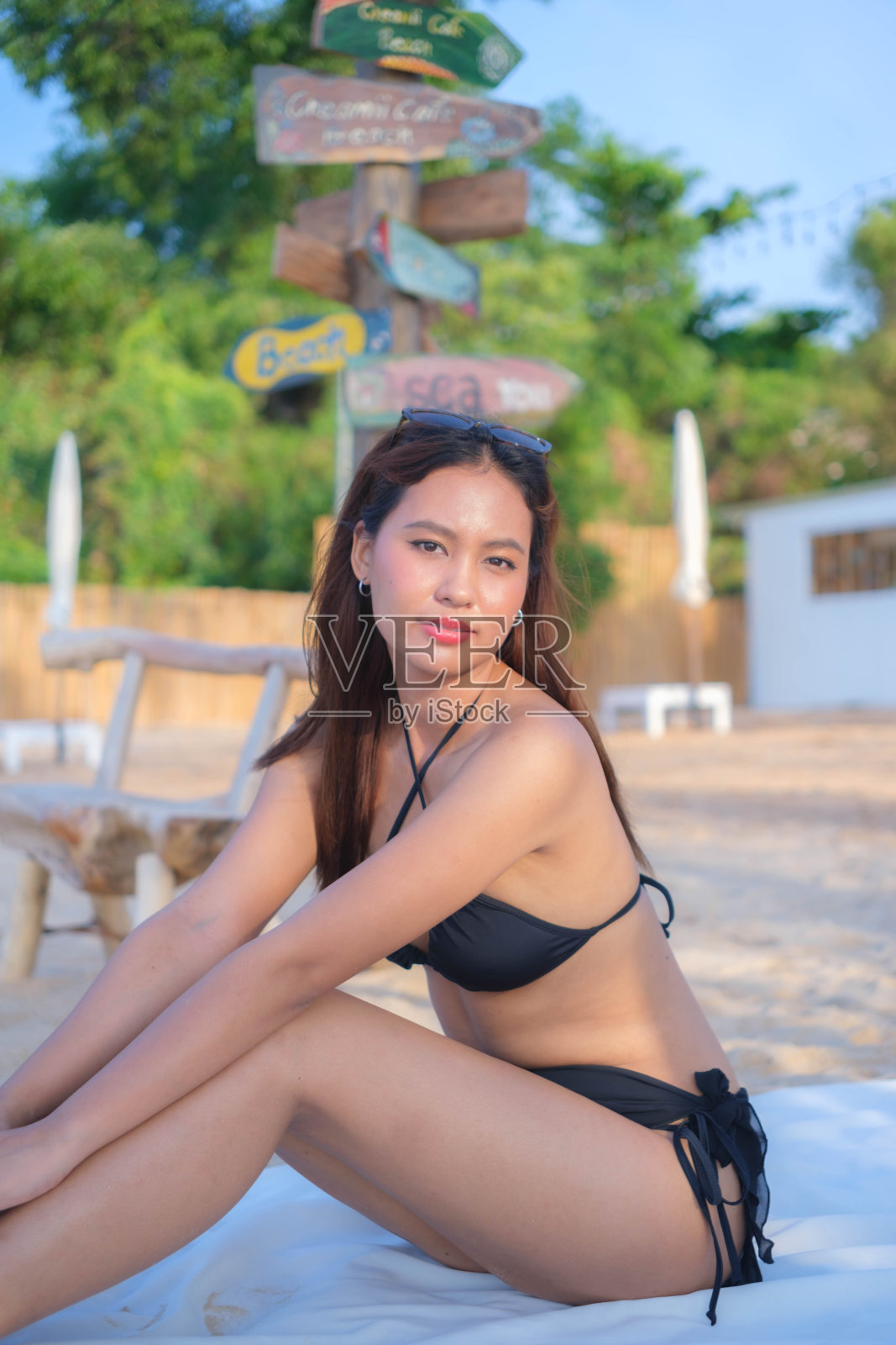 美丽的年轻亚洲女子坐在海边的一块白布上照片摄影图片