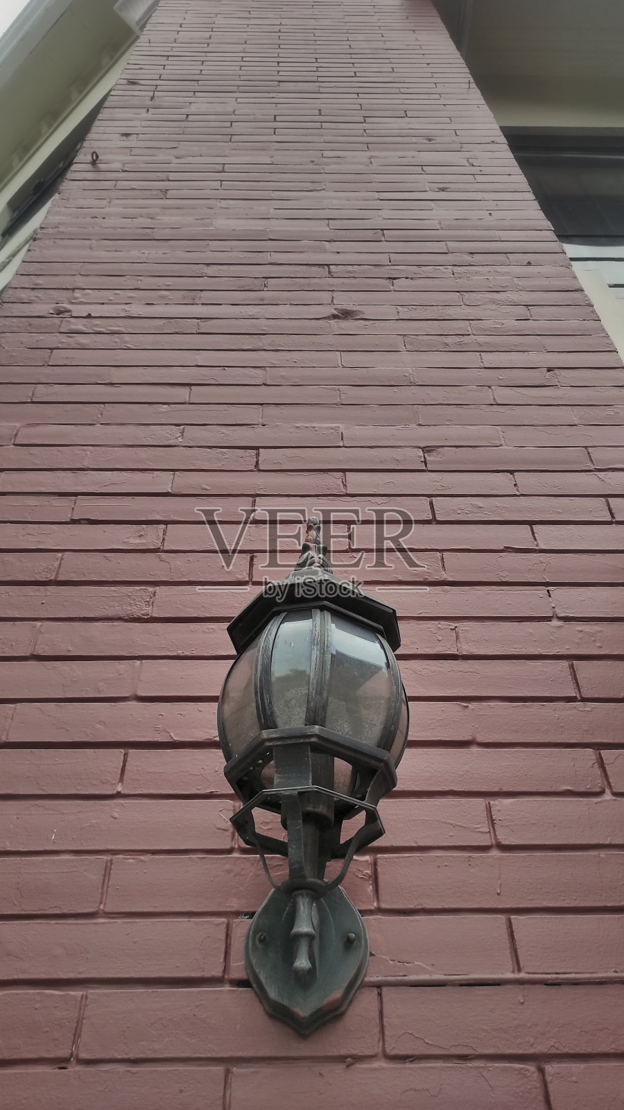 市区建筑物的红砖墙上挂着一盏古老的黑色古灯照片摄影图片