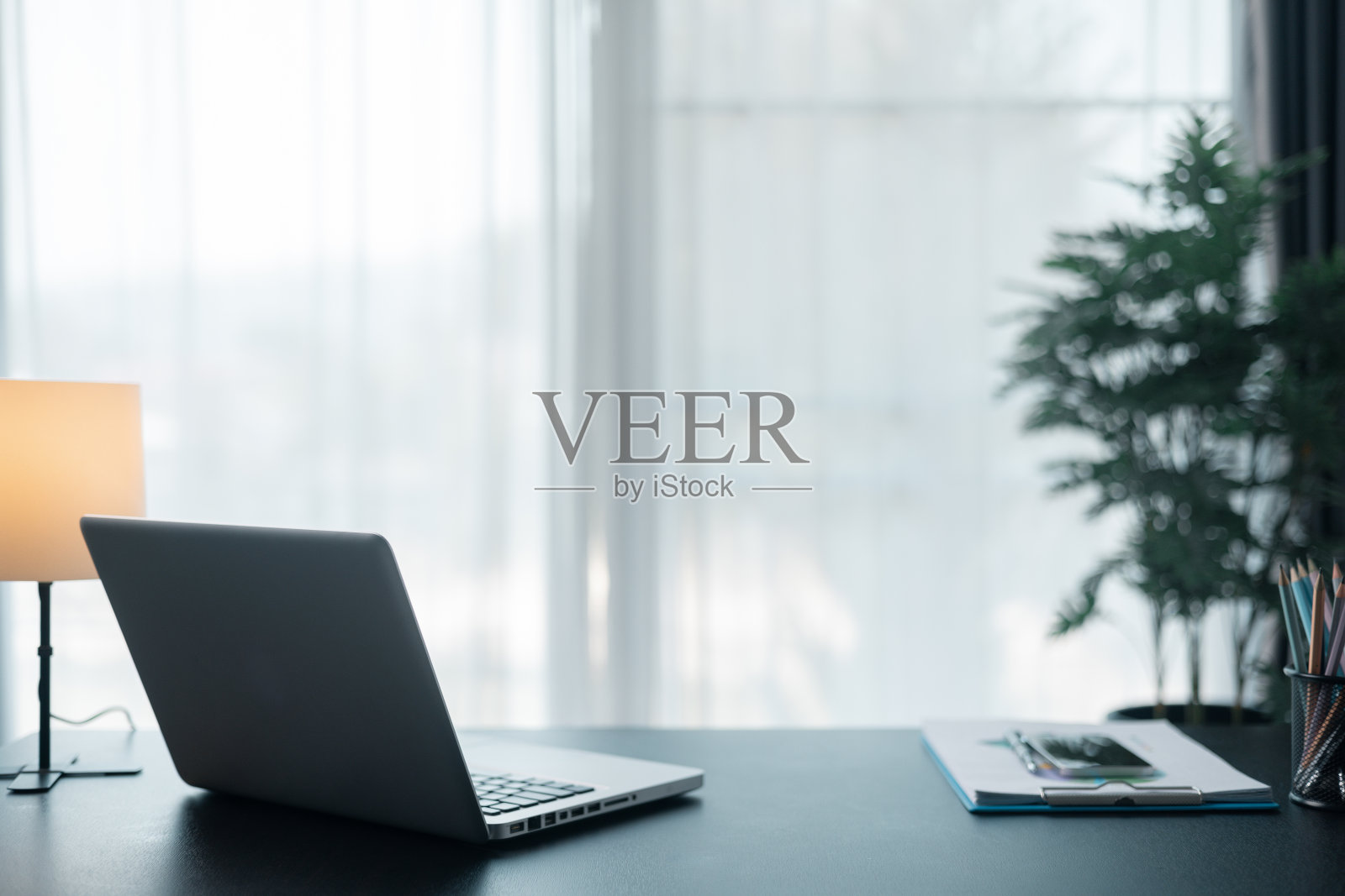 办公场所,笔记本电脑和智能手机放在木桌上。工作空间,台式电脑,办公用品,室内植物和办公室书籍。案头工作概念。在办公室舒适的工作台。照片摄影图片