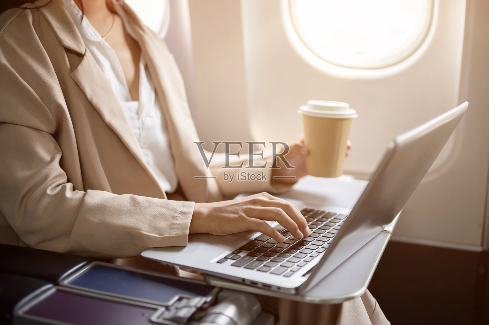 在飞机上,一位勤劳的女商人正在用笔记本电脑工作。照片摄影图片