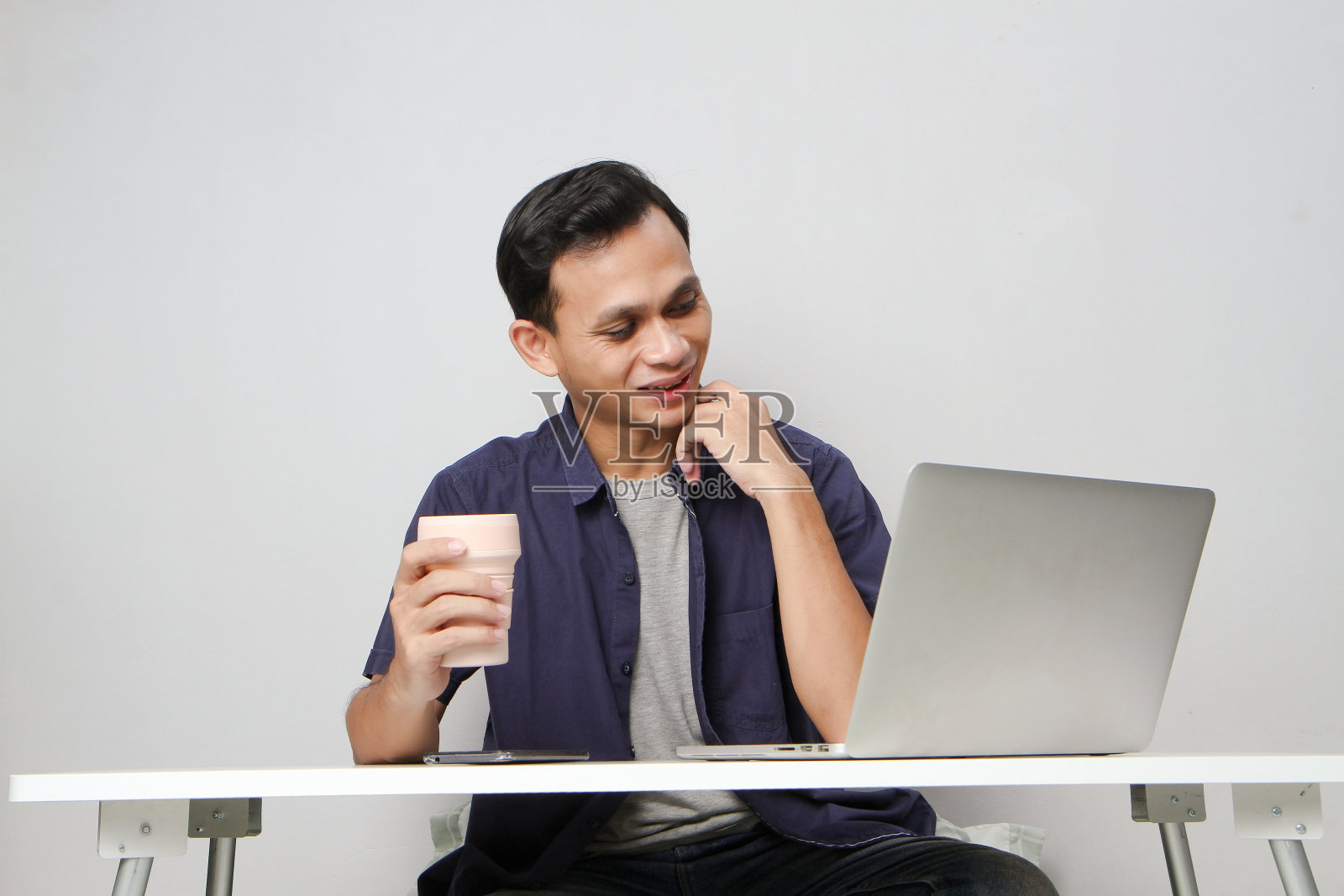 快乐的亚洲人在工作场所坐在笔记本电脑前。在孤立的背景下照片摄影图片