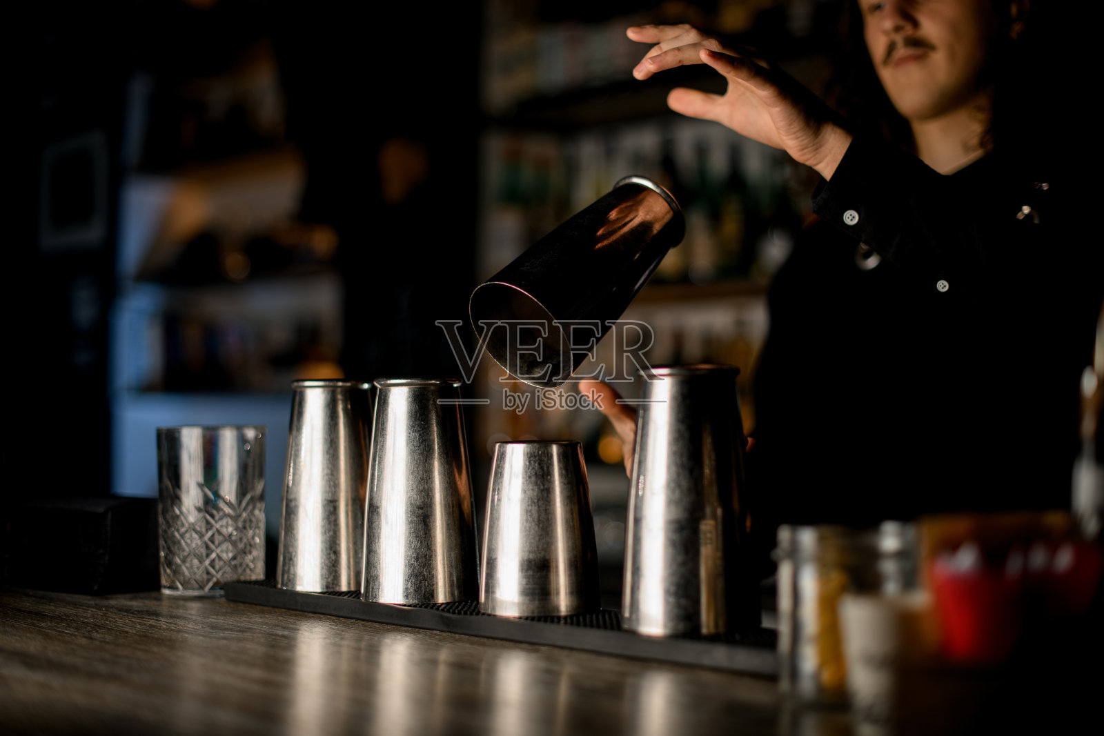 年轻的酒保扔出一个调酒杯,接住了照片摄影图片