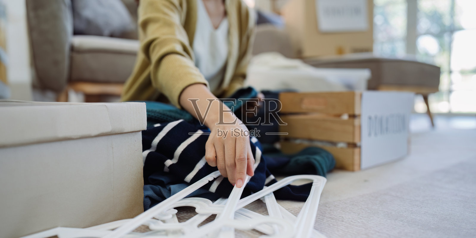 亚洲年轻女子在家里收拾衣服,把衣服放进装有二手衣服的捐赠箱。帮助穷人。捐赠的概念照片摄影图片