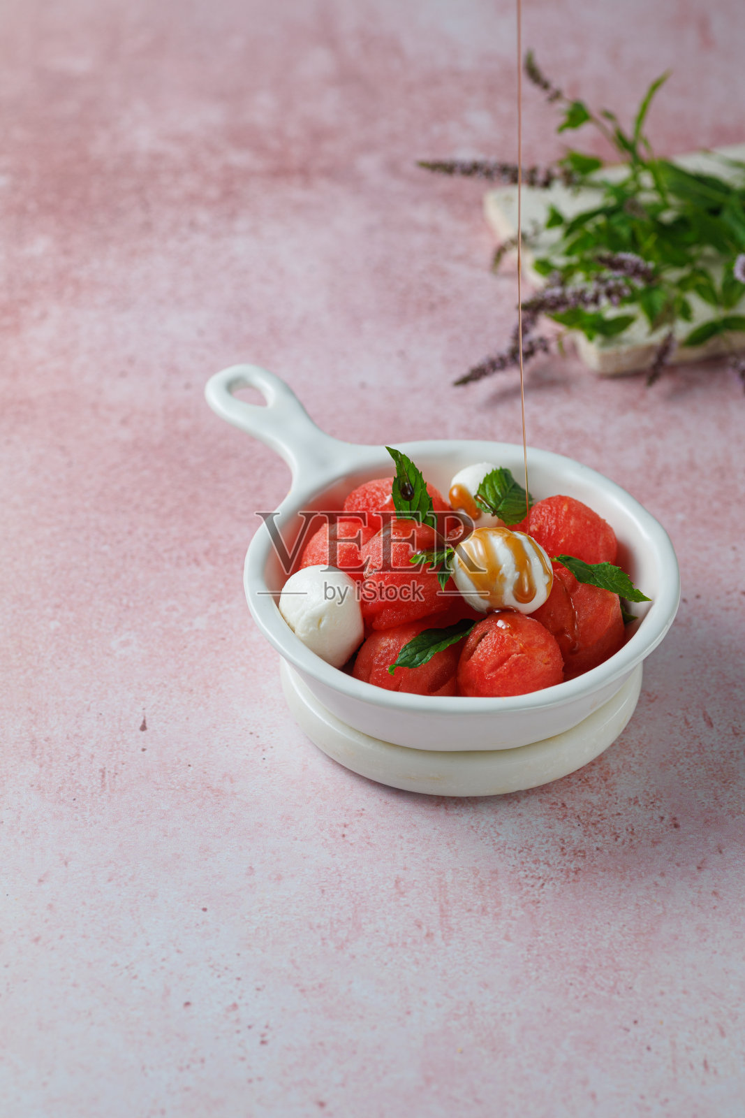 水果沙拉配西瓜球和马苏里拉奶酪,白色陶瓷碗,浅玫瑰色背景照片摄影图片