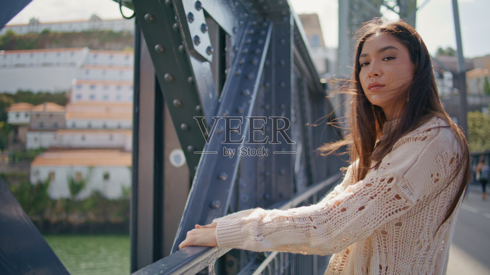 诱人的女士站在桥上把脸放在阳光下的特写。女人的肖像照片摄影图片