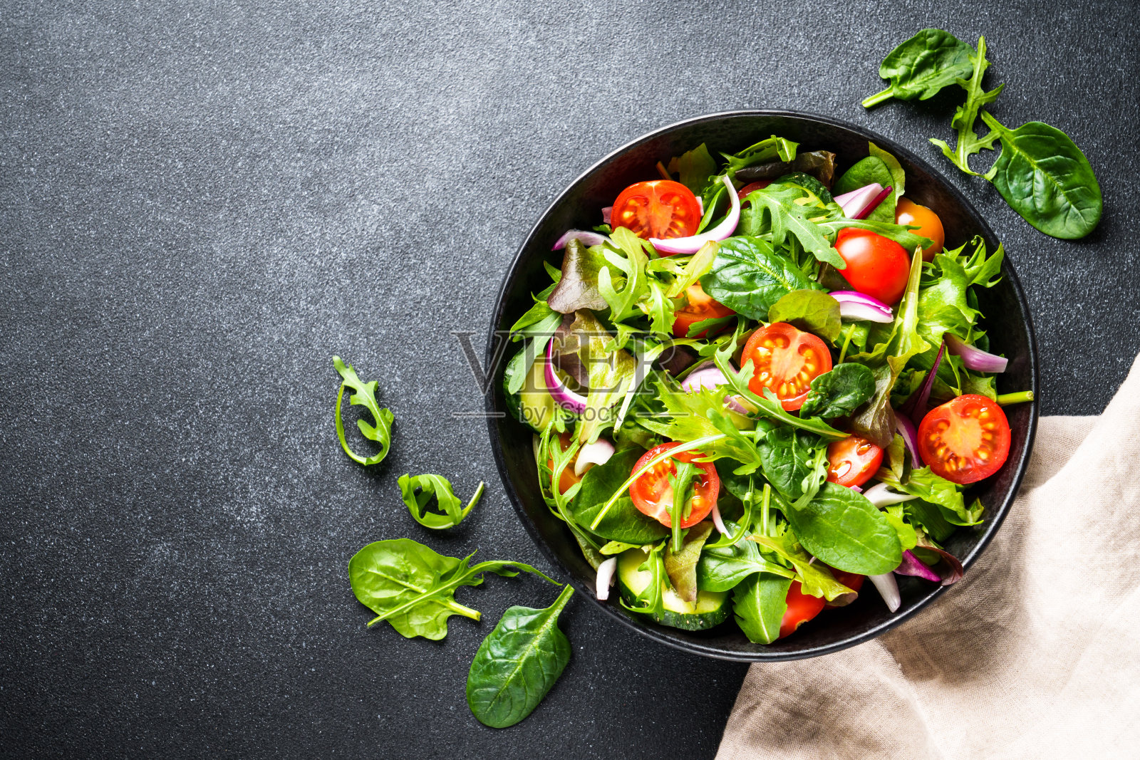 沙拉在黑色的碗在黑暗的背景。照片摄影图片