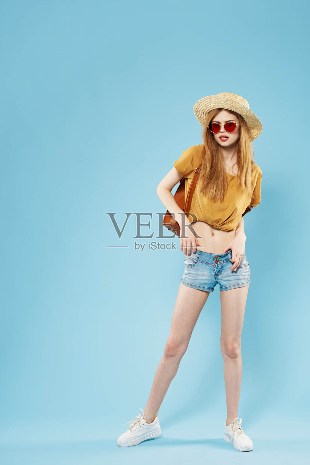 漂亮的女人优雅的风格帽子太阳镜摆出蓝色的背景照片摄影图片