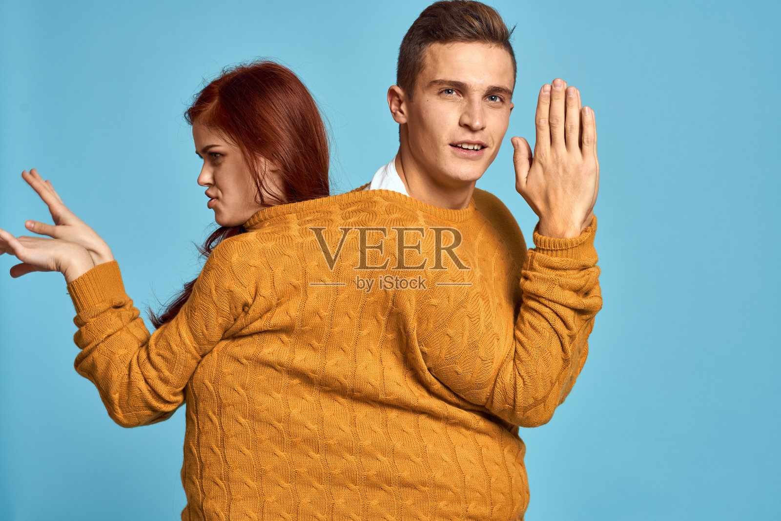 一对穿着黄色毛衣的夫妇在蓝色背景下摆姿势照片摄影图片