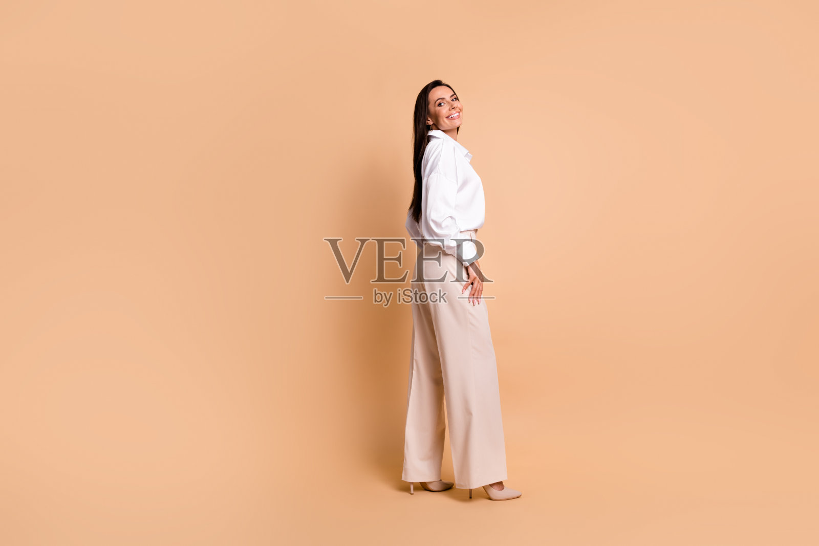 令人惊叹的正面女士的全身侧面照片摆出优雅的衣服,空白的空间孤立在米色背景上照片摄影图片