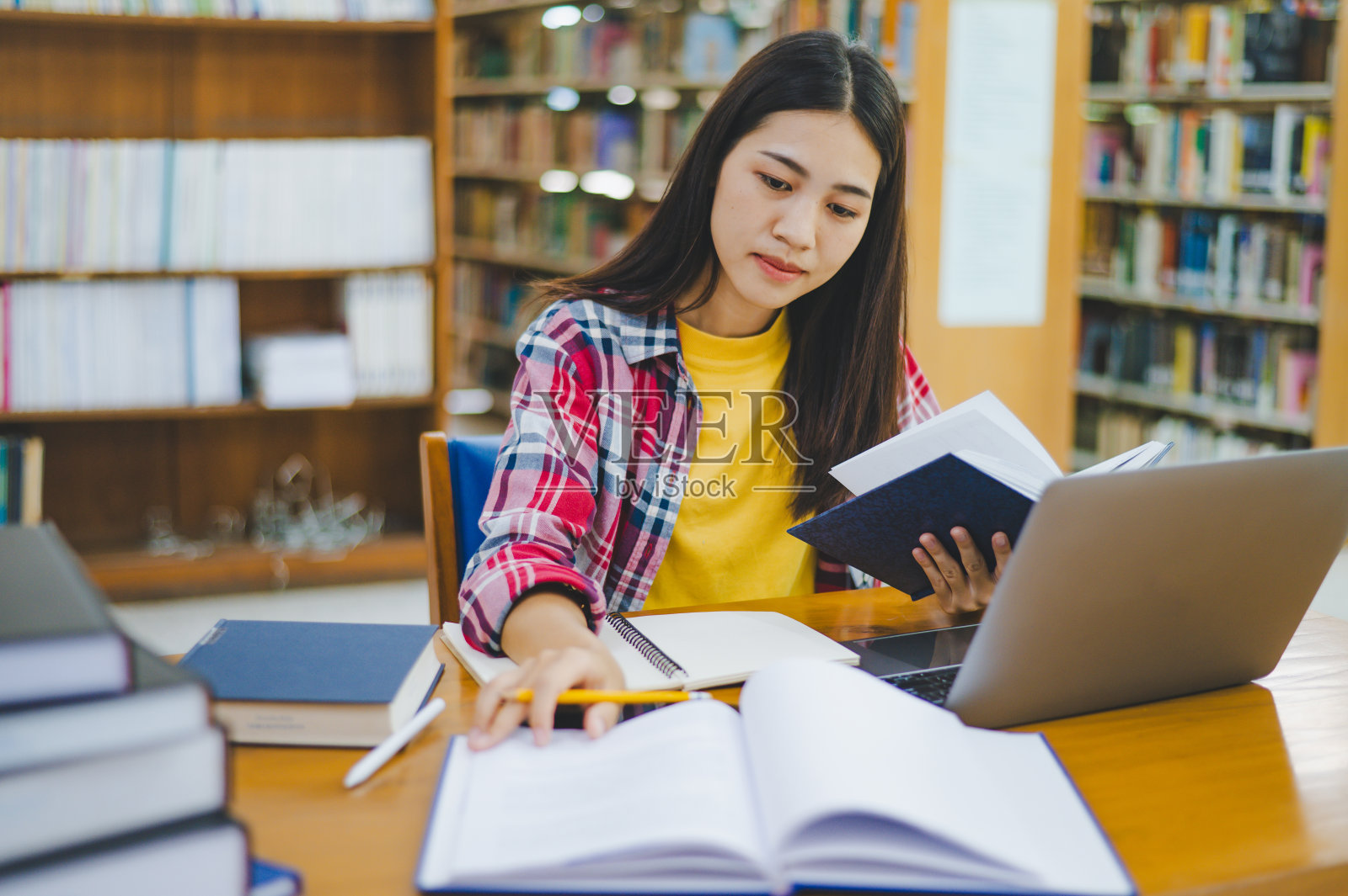 女大学生使用笔记本电脑,在教室里找书学习,做报告,查找有用的信息。读书、学习、智慧的概念。照片摄影图片