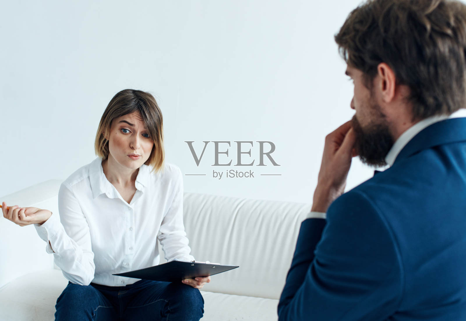一个穿着经典西装的商人和一个坐在沙发上手里拿着心理学家文件的女人照片摄影图片