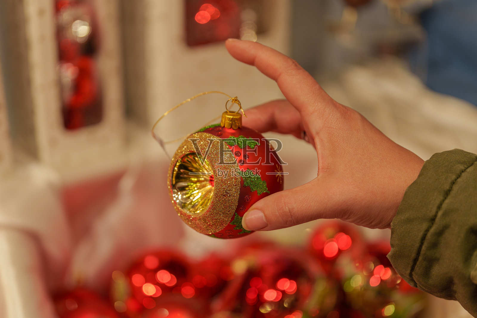 一位女士手里拿着一个红色和金色相间的圣诞装饰球照片摄影图片