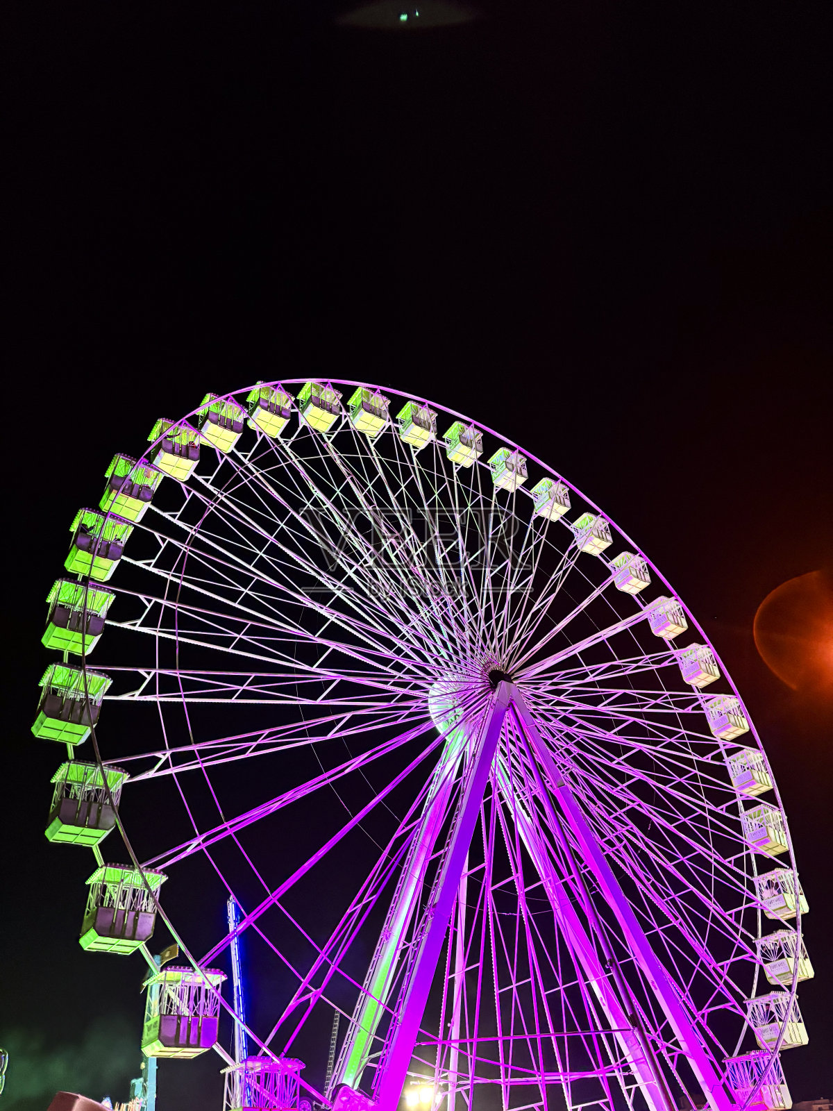 游乐园夜间的摩天轮在运动。假日的概念和人们玩得开心。夜生活的假期。照片摄影图片