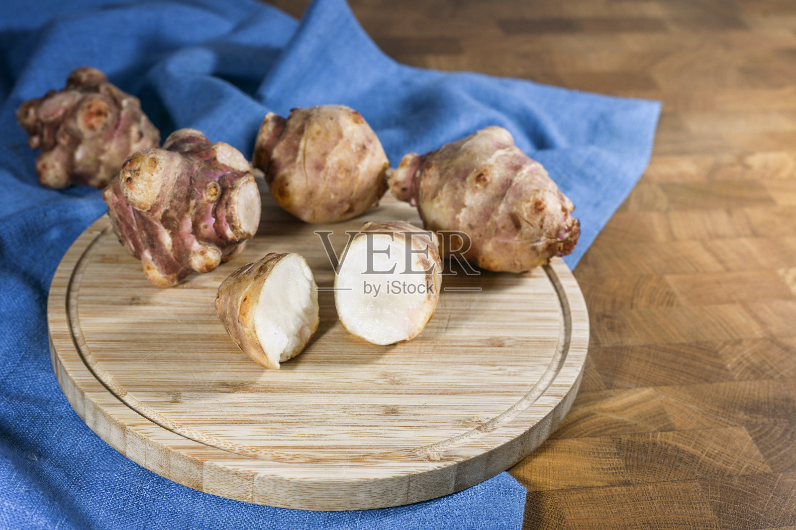 根茎类蔬菜耶路撒冷洋蓟或洋蓟(Helianthus tuberosus),整棵和半棵放在一个质朴的木制厨房板和蓝色餐巾上,用于健康饮食和糖尿病,复制空间照片摄影图片