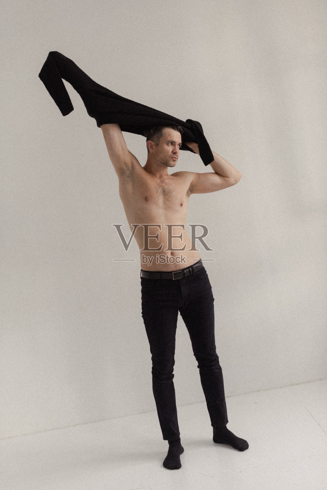 那人脱下衣服,脱掉他的黑毛衣照片摄影图片