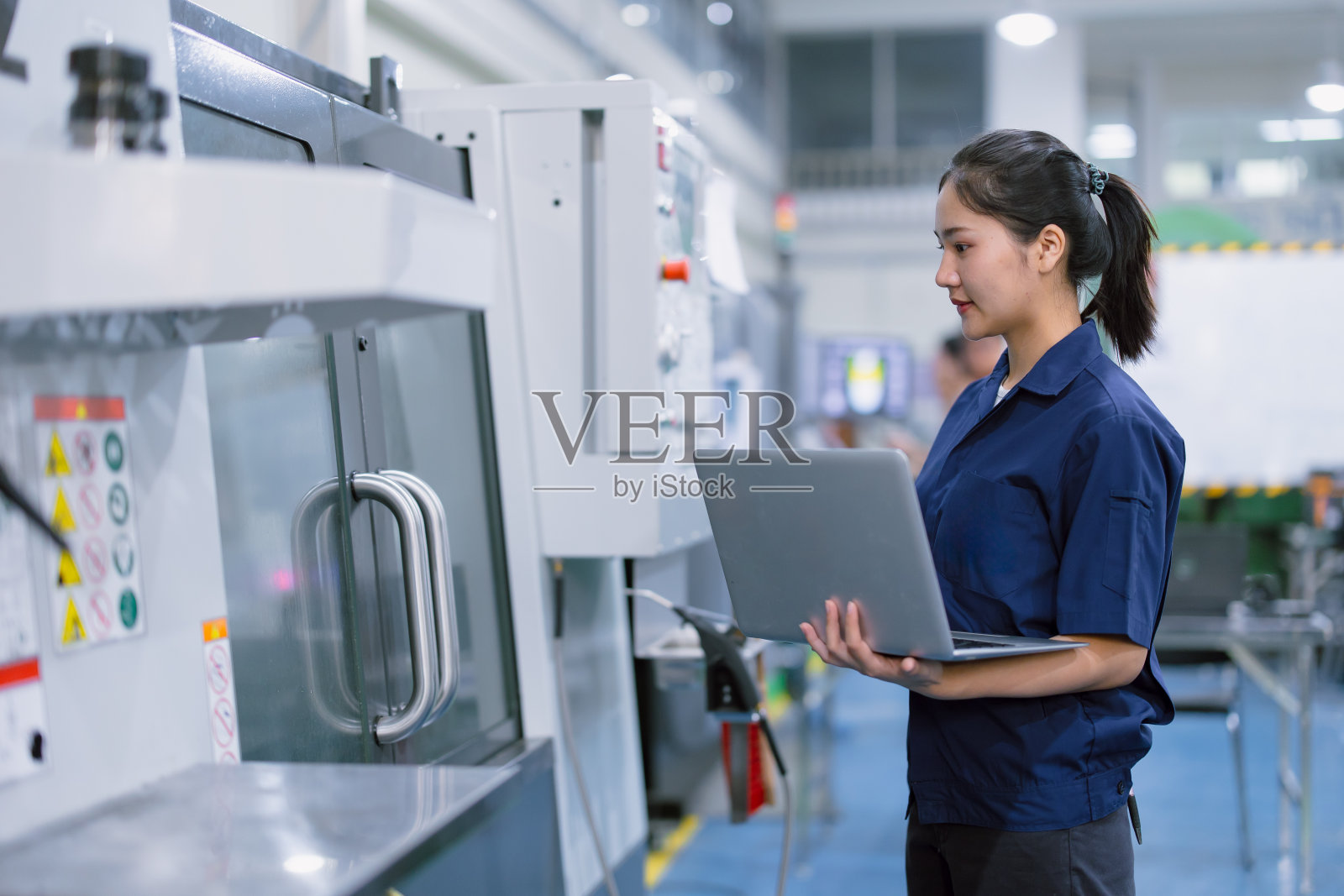 亚洲女工在钢铁制品厂从事重工业,操作数控车床、铣床照片摄影图片