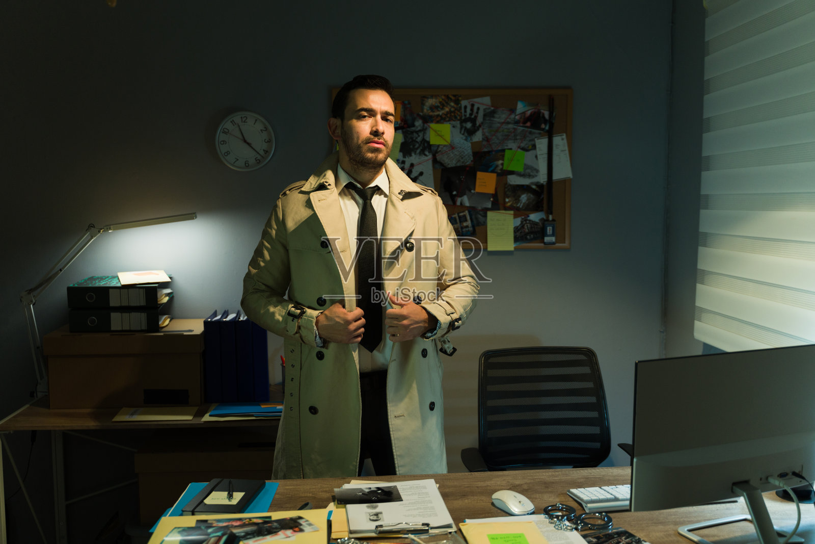 在昏暗的办公室里穿着风衣的自信侦探照片摄影图片