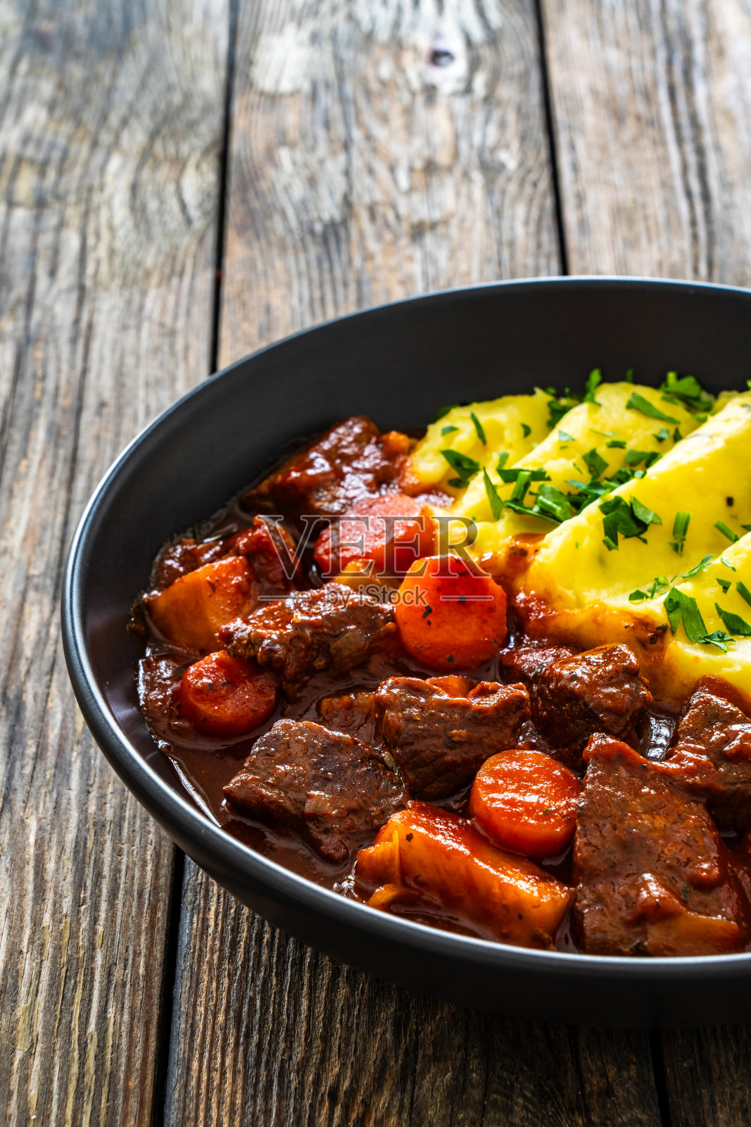 圣帕特里克节的爱尔兰炖菜——啤酒烤牛肉和土豆泥放在木桌上照片摄影图片
