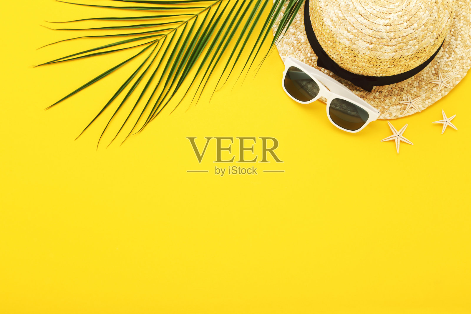 草帽和太阳镜,海星和棕榈叶在黄色的背景照片摄影图片