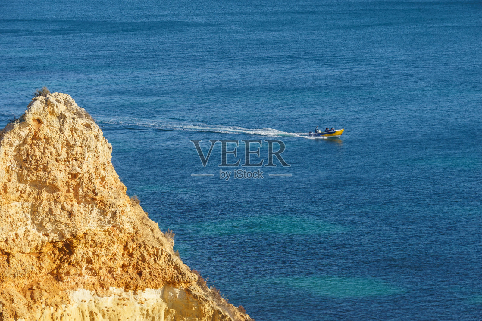 在葡萄牙阿尔加维贝纳吉尔洞穴附近大西洋海岸线的金色悬崖上乘船。照片摄影图片