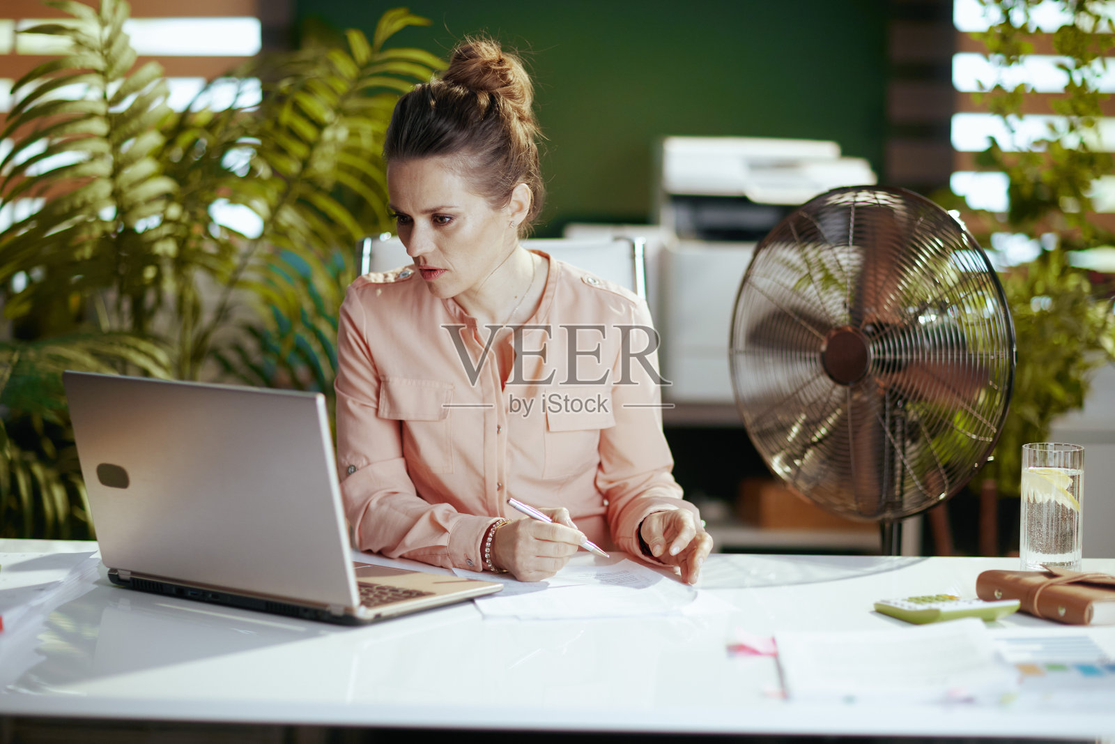 在绿色办公室里忧虑的40岁女老板照片摄影图片