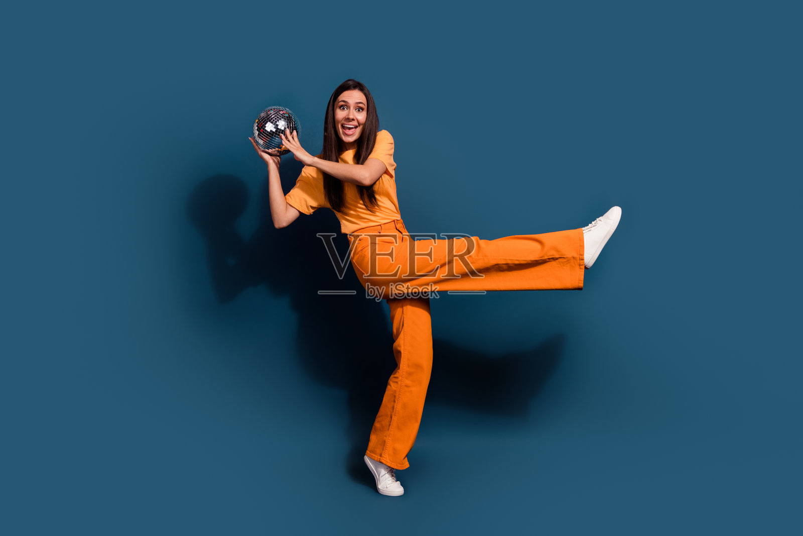 疯狂女孩穿着橙色的全身照片看起来很开心,迪斯科球布吉伍吉在深蓝色的背景上被隔离照片摄影图片