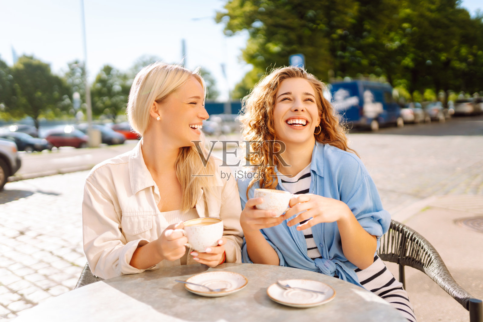一个微笑的年轻女性朋友坐在户外咖啡馆喝咖啡的肖像。照片摄影图片