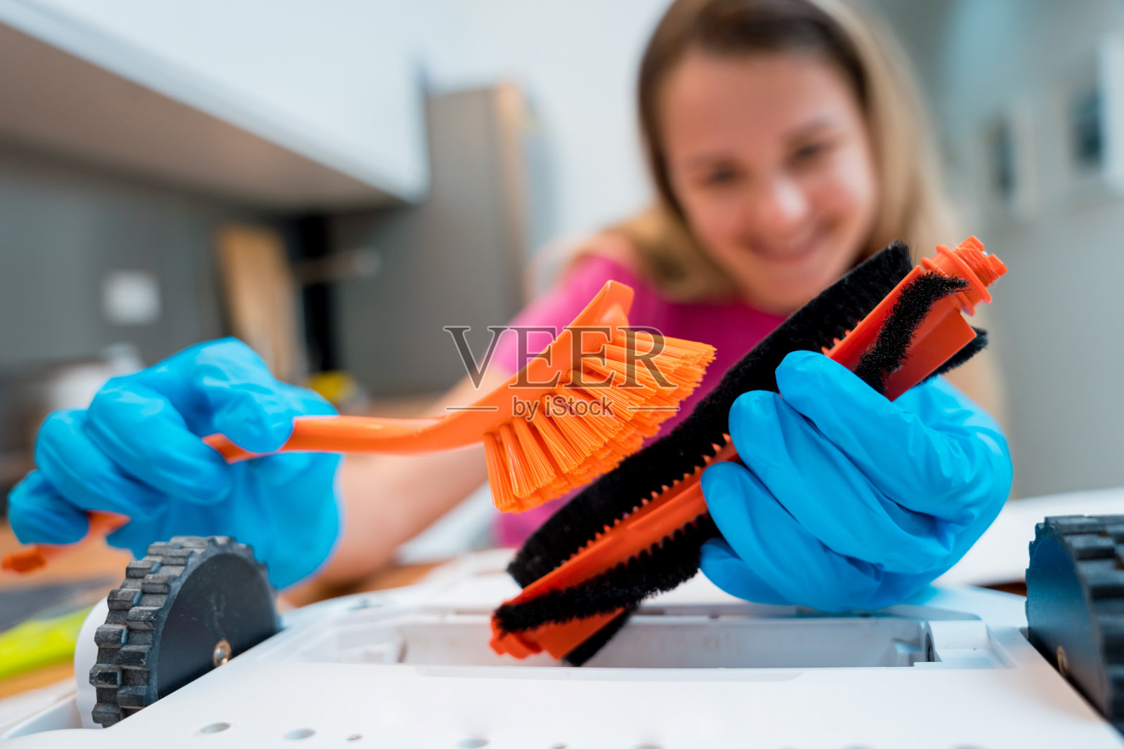 一名年轻女子清洁机器人吸尘器后的污垢。照片摄影图片